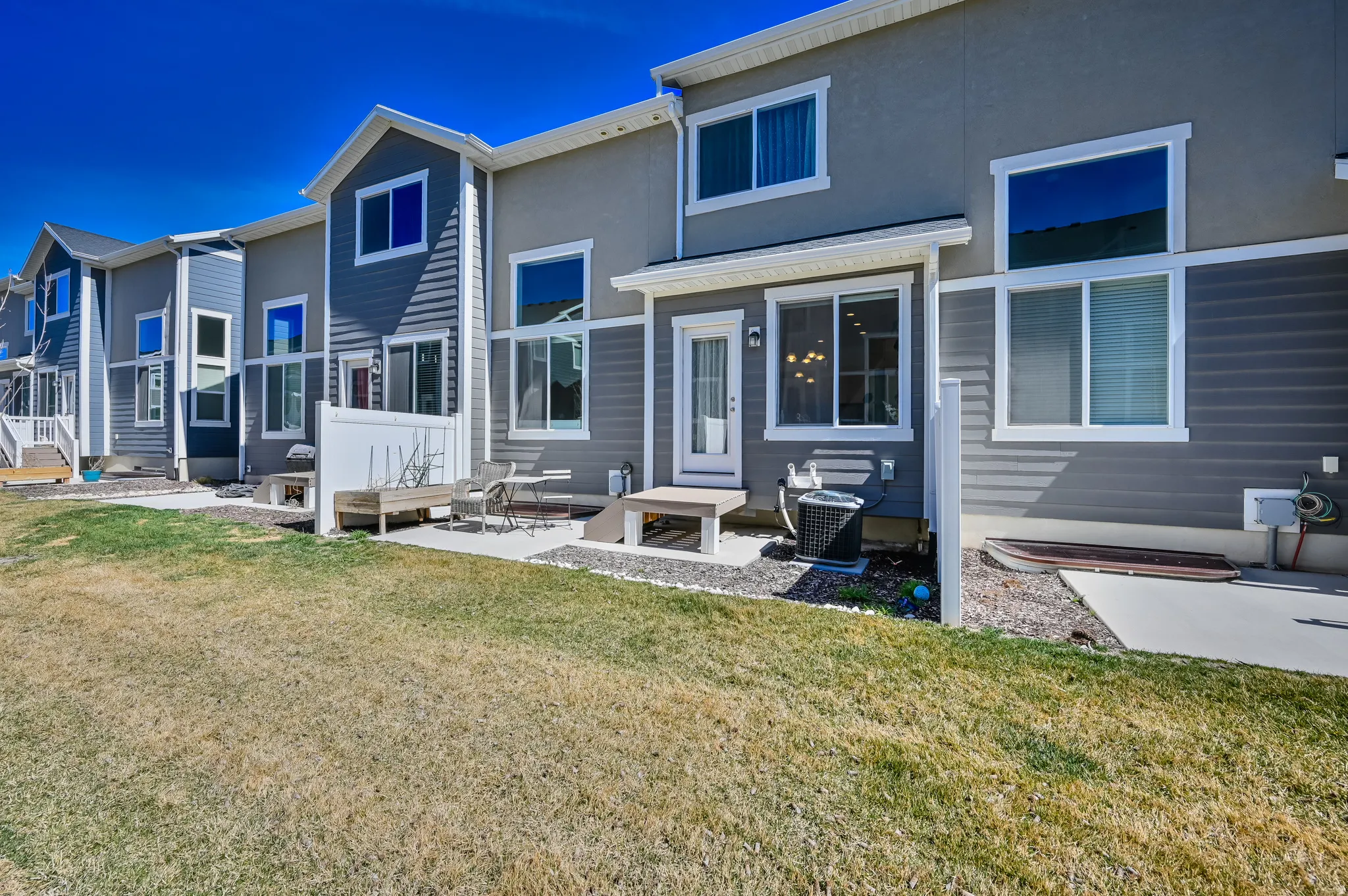 Rear exterior featuring a private patio, white vinyl fencing, and a combination of horizontal siding and stucco finishes
