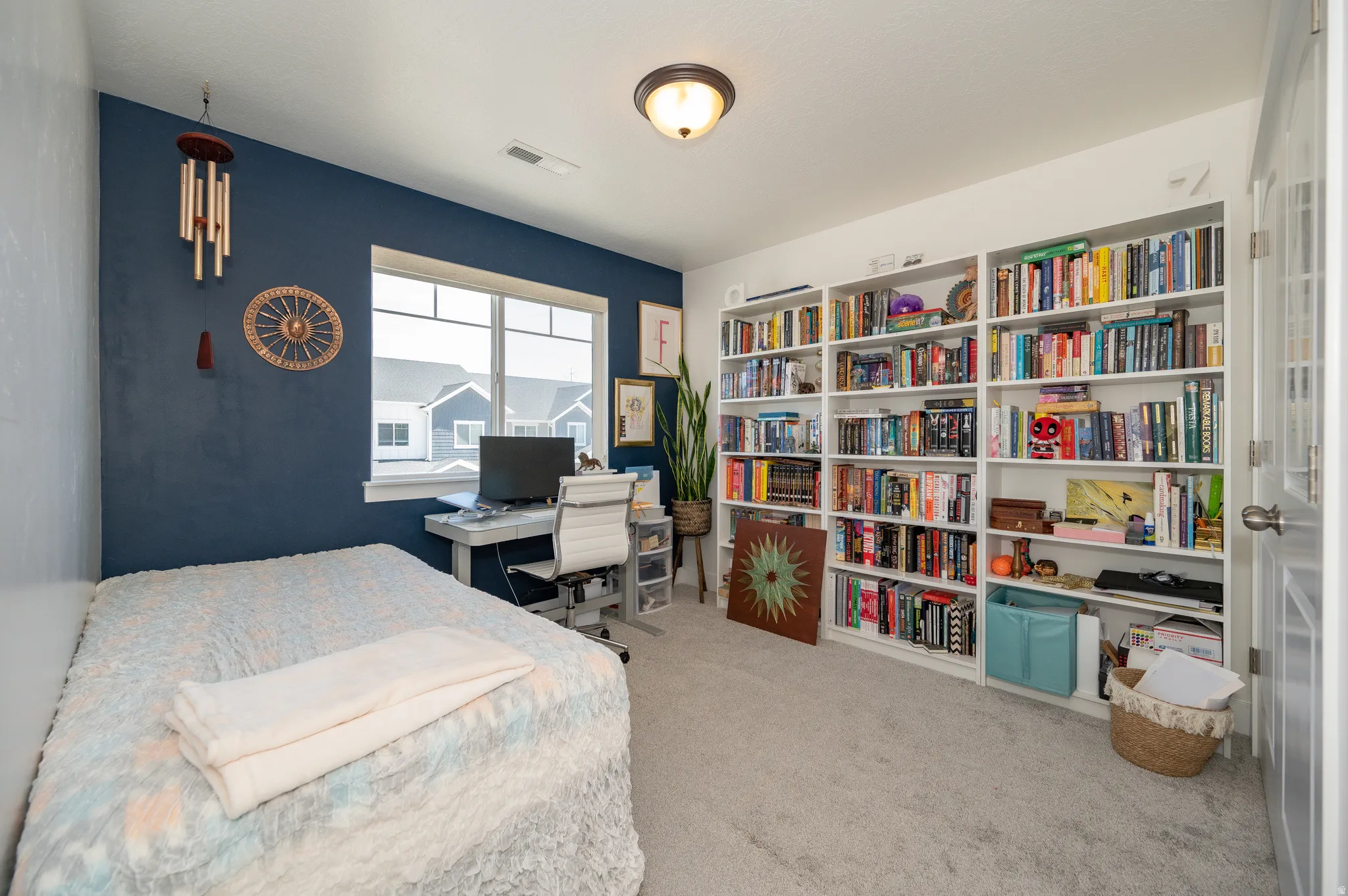 Spacious room featuring a large window, built-in shelving, plush carpet flooring, and a modern ceiling light fixture