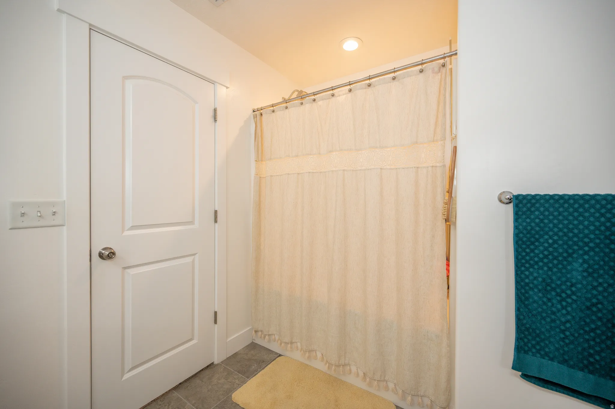 Bathroom featuring a white paneled door, light gray floor tiling, and a recessed ceiling light