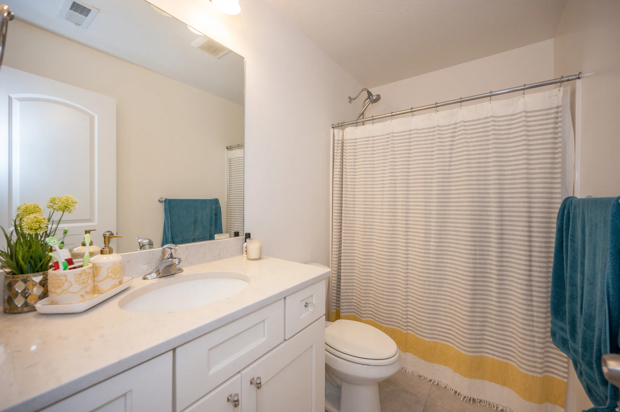 Bathroom featuring a white vanity with an integrated sink and light-toned countertop, a frameless wall mirror, and a shower with a chrome showerhead