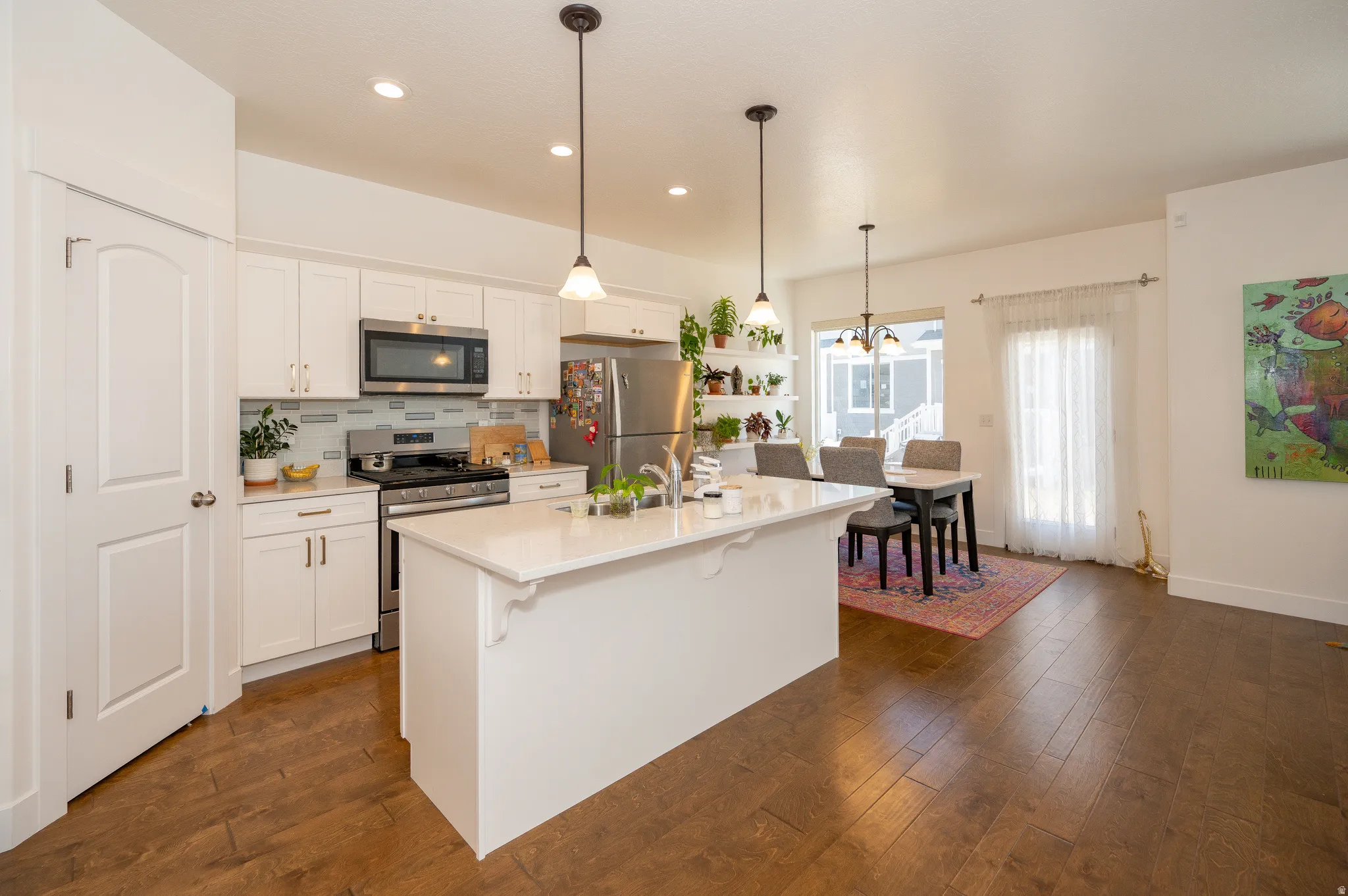 Modern kitchen featuring white cabinetry, stainless steel appliances, a tile backsplash, and a central island with countertop seating