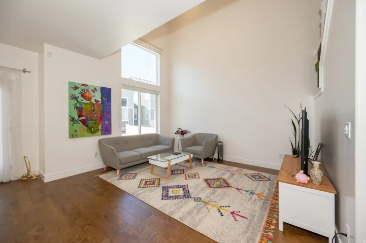 Living area featuring soaring ceilings, hardwood-finish flooring, and abundant natural light from tall windows