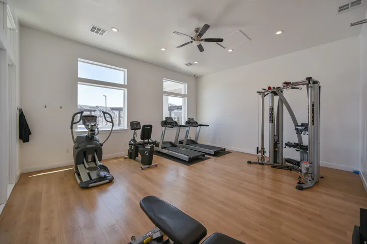 Dedicated fitness space featuring wood-finish flooring and abundant natural light from multiple windows