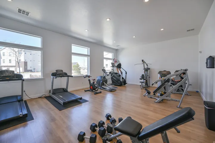 Dedicated fitness space featuring wood-finish flooring, ample natural light from multiple windows, recessed ceiling lighting, and crisp white walls
