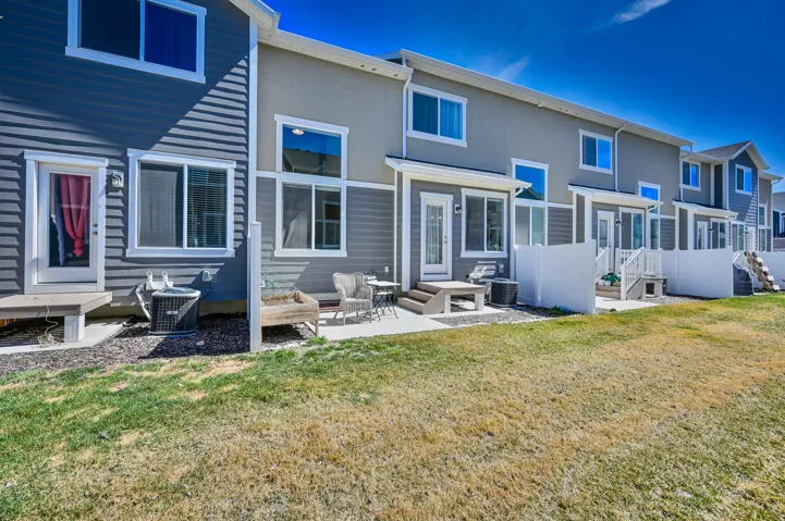 Rear exterior featuring a concrete patio, white privacy fences, and multiple large windows