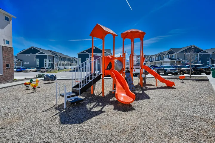 Community playground featuring an orange play structure with multiple slides and climbing elements
