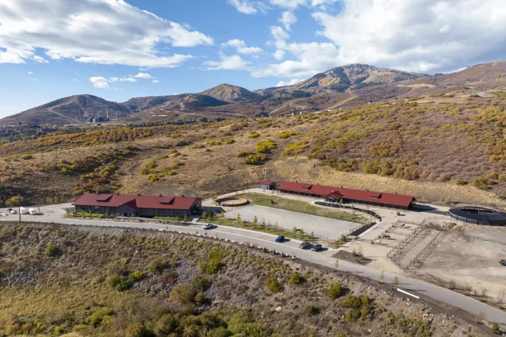 Sprawling equestrian facility featuring multiple structures with red roofs, extensive outdoor riding arenas, fenced paddocks, and a round pen