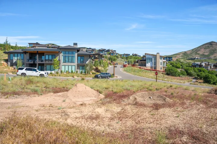 Modern hillside residence featuring expansive window walls, multiple balconies, and a stone and wood exterior