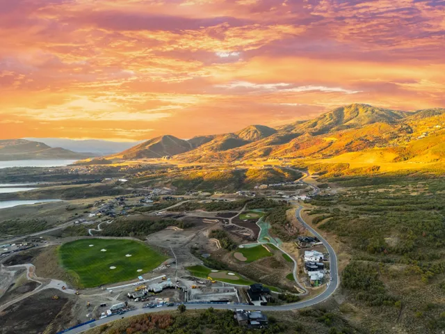 Expansive aerial landscape featuring a golf course, surrounding residential properties, and distant water bodies