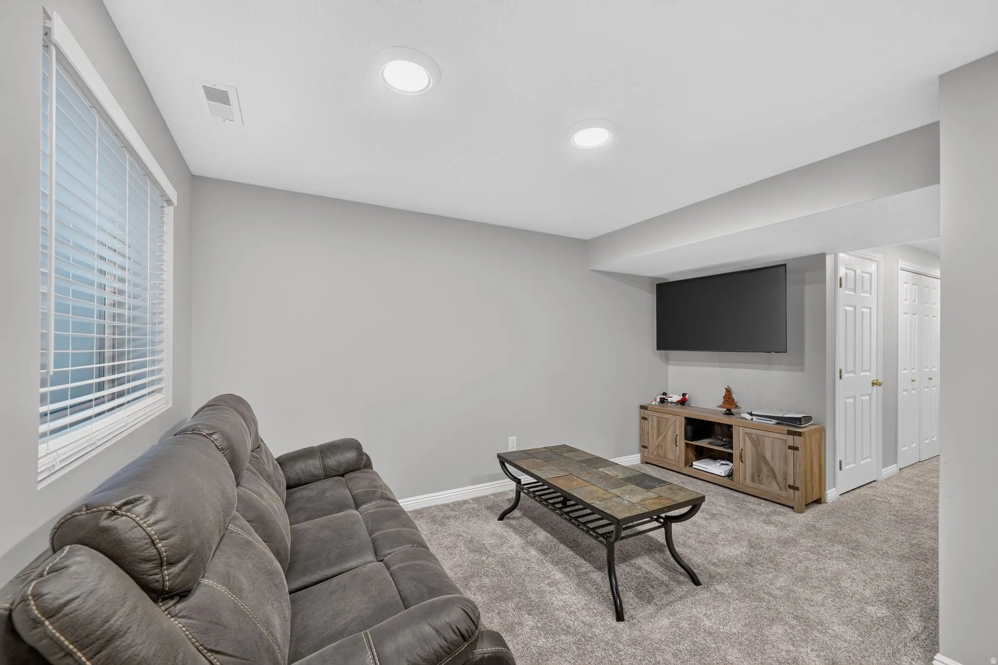 Finished room featuring recessed lighting, light gray walls, window with blinds, and neutral carpeting
