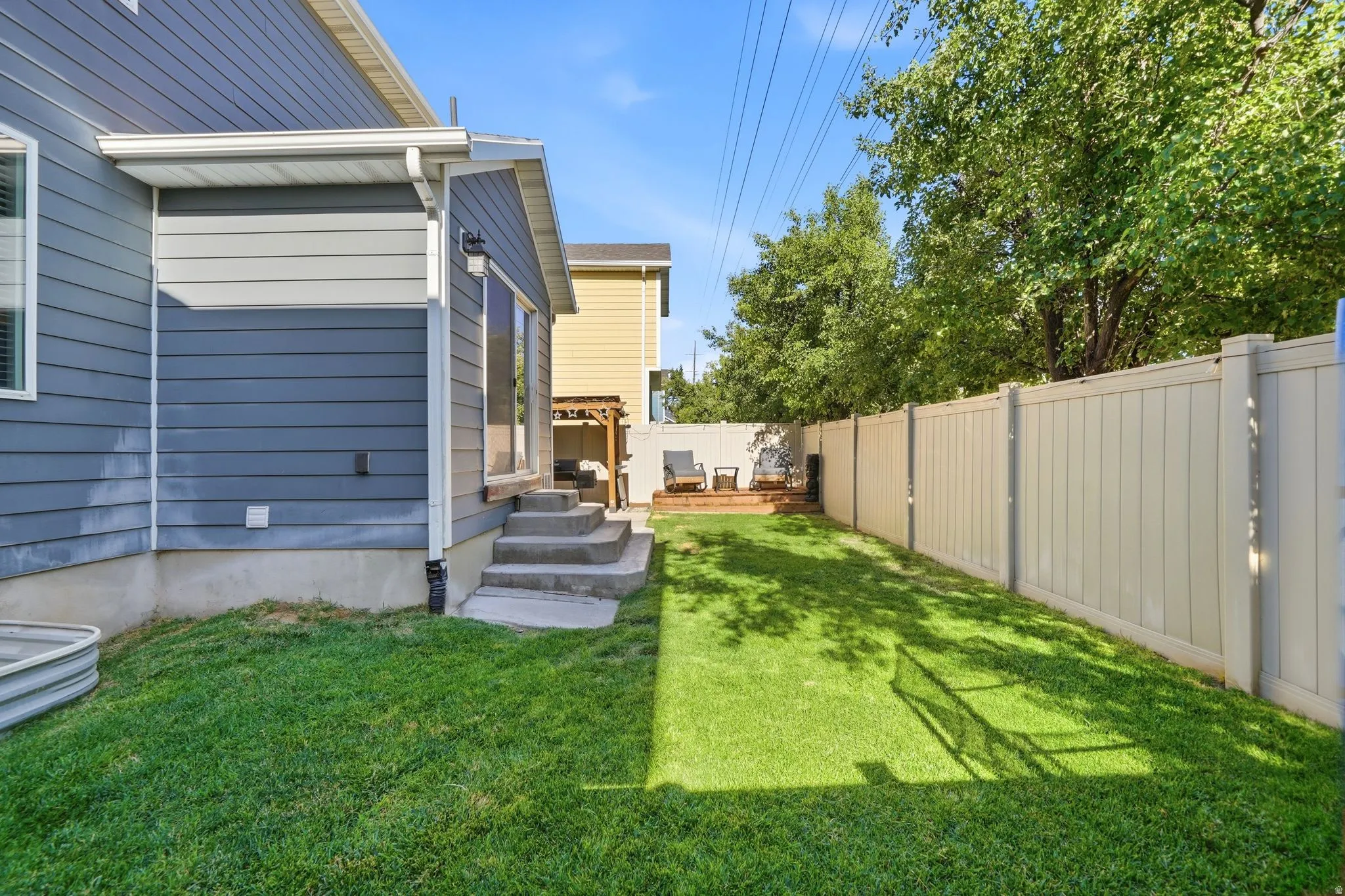Private backyard featuring a manicured lawn, concrete steps, and a durable privacy fence