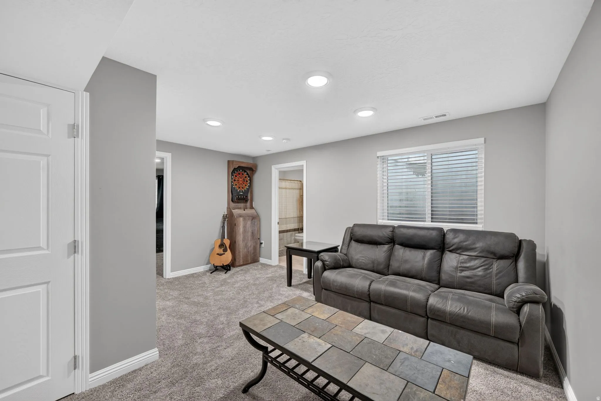 Carpeted living space featuring recessed lighting, a window with blinds, and white trim