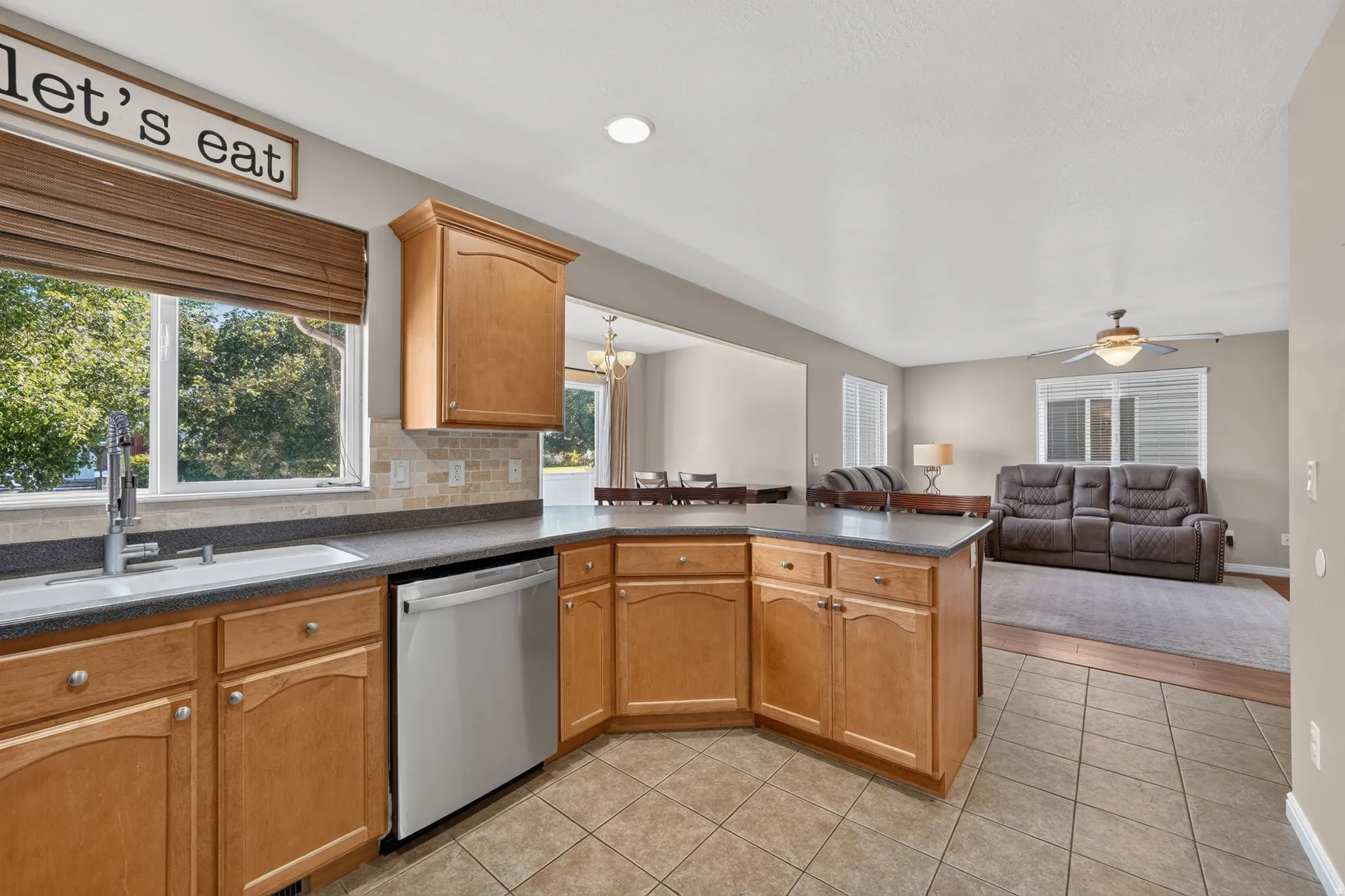 Kitchen featuring light wood cabinetry with brushed nickel hardware, solid surface countertops, and a tile backsplash