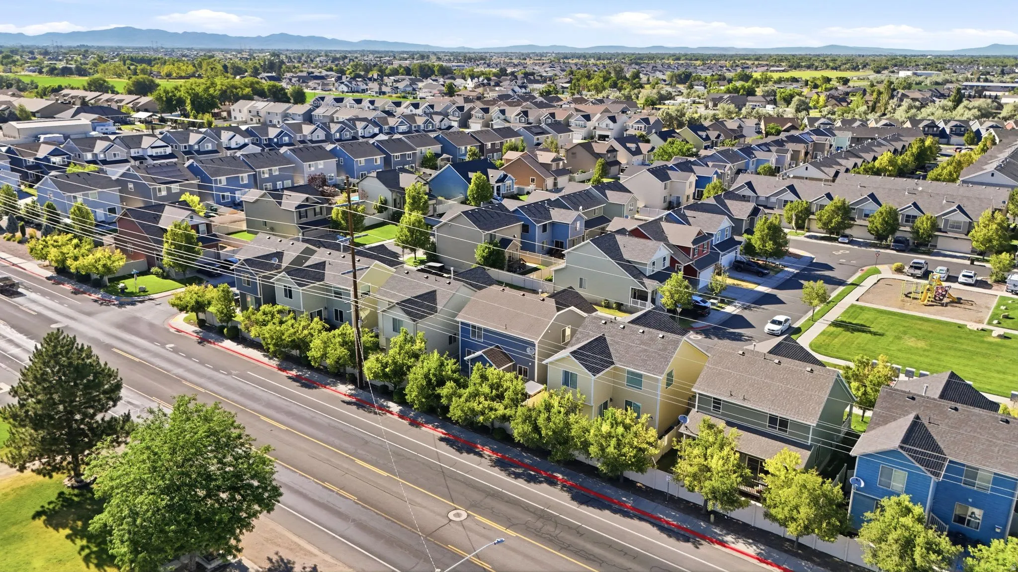 Expansive aerial panorama showcasing a residential development with numerous multi-story homes featuring varied exterior colors and dark-toned roofs