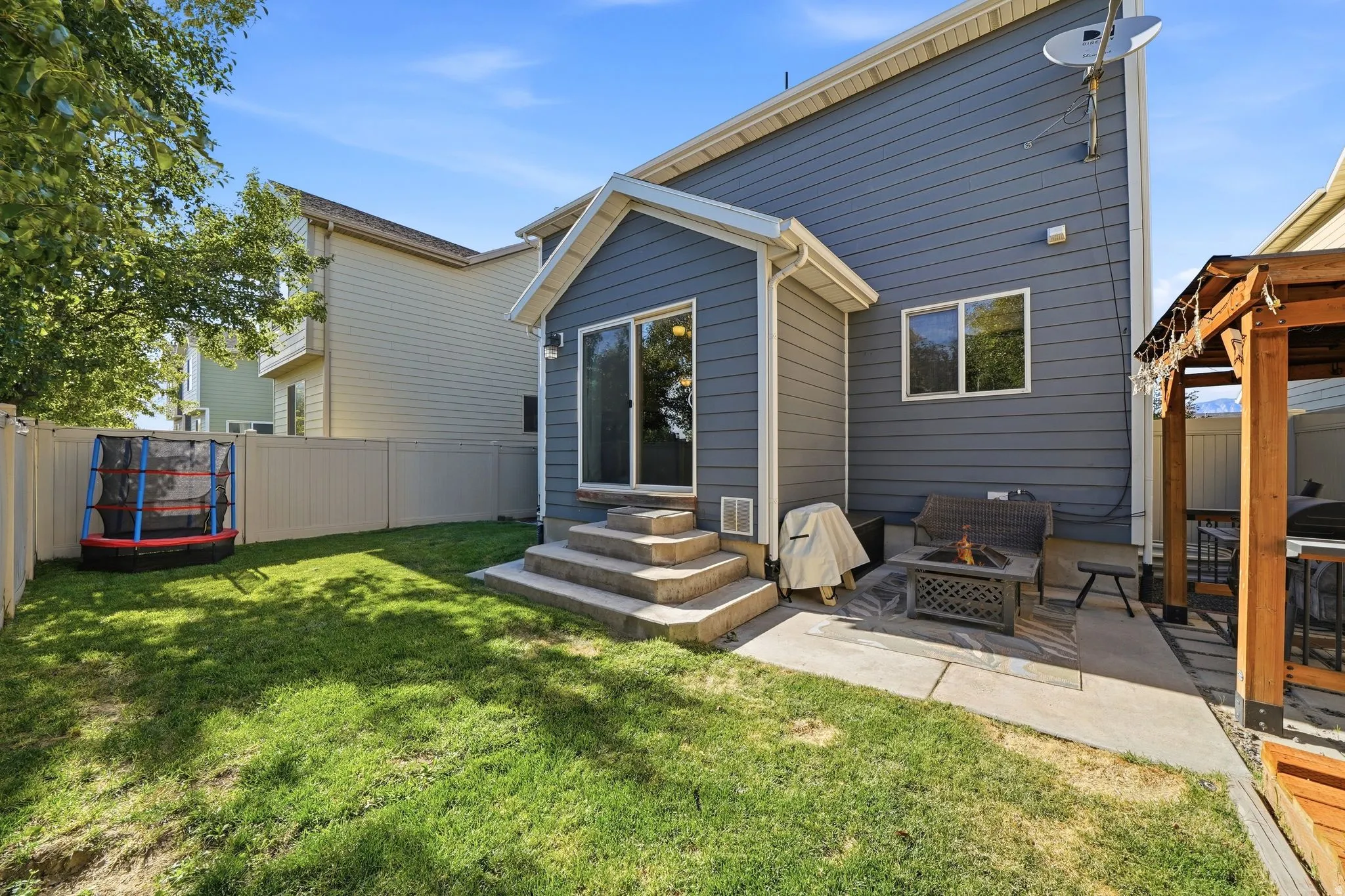 Fenced backyard featuring a manicured lawn, concrete patio, and a covered outdoor structure