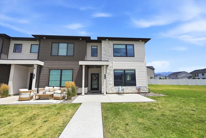 Contemporary townhome exterior featuring mixed material facade with stone accents, dark frame windows, and a paved walkway