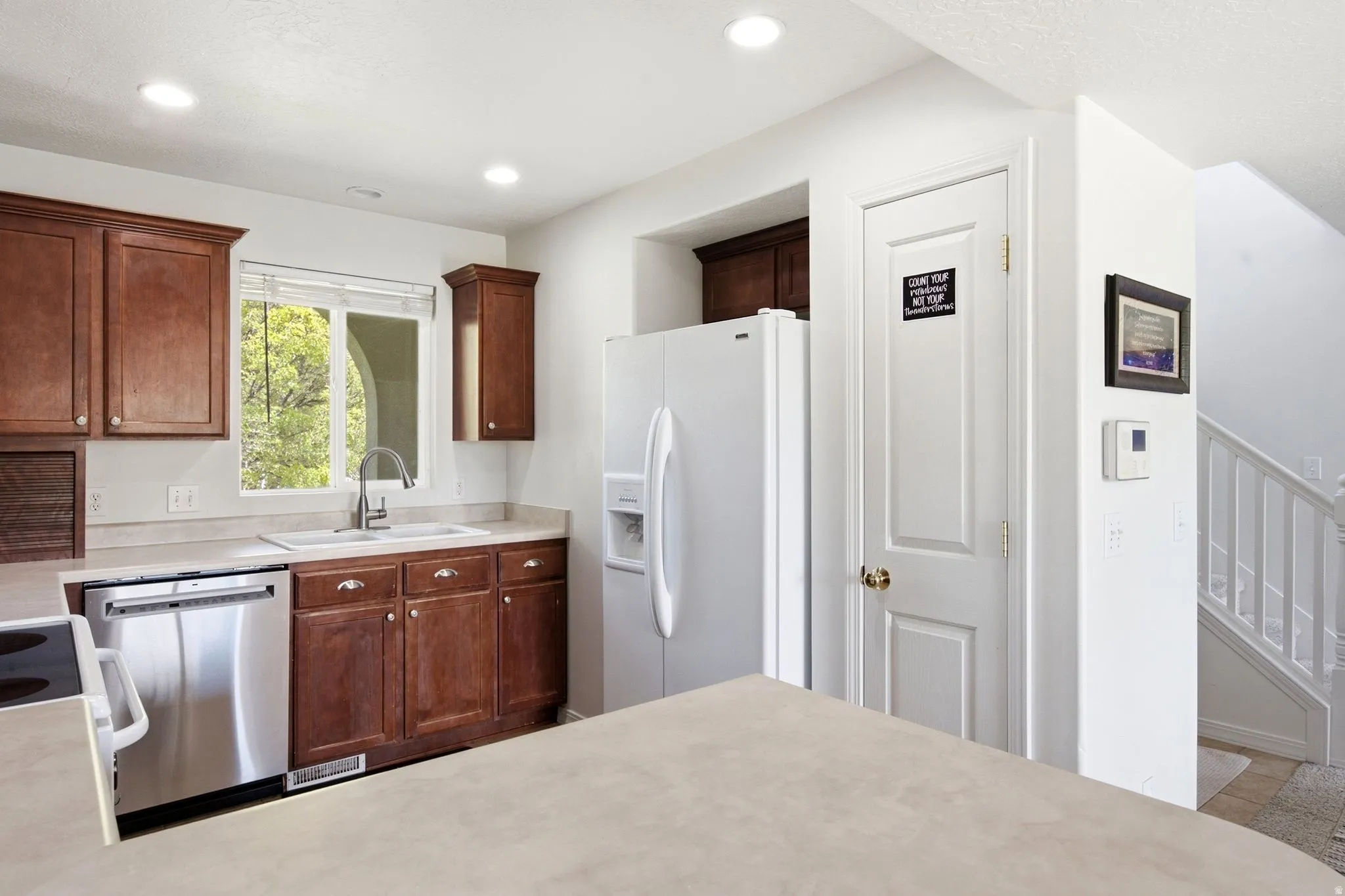 Kitchen featuring wood cabinetry, stainless steel dishwasher, white refrigerator, and recessed lighting