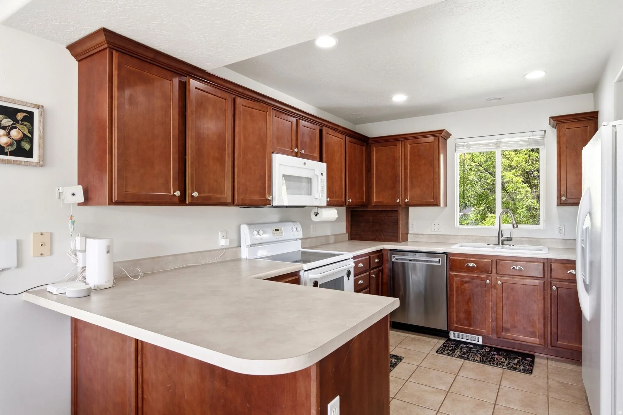 Kitchen featuring wood-finish cabinetry, neutral countertops, recessed lighting, and tile flooring