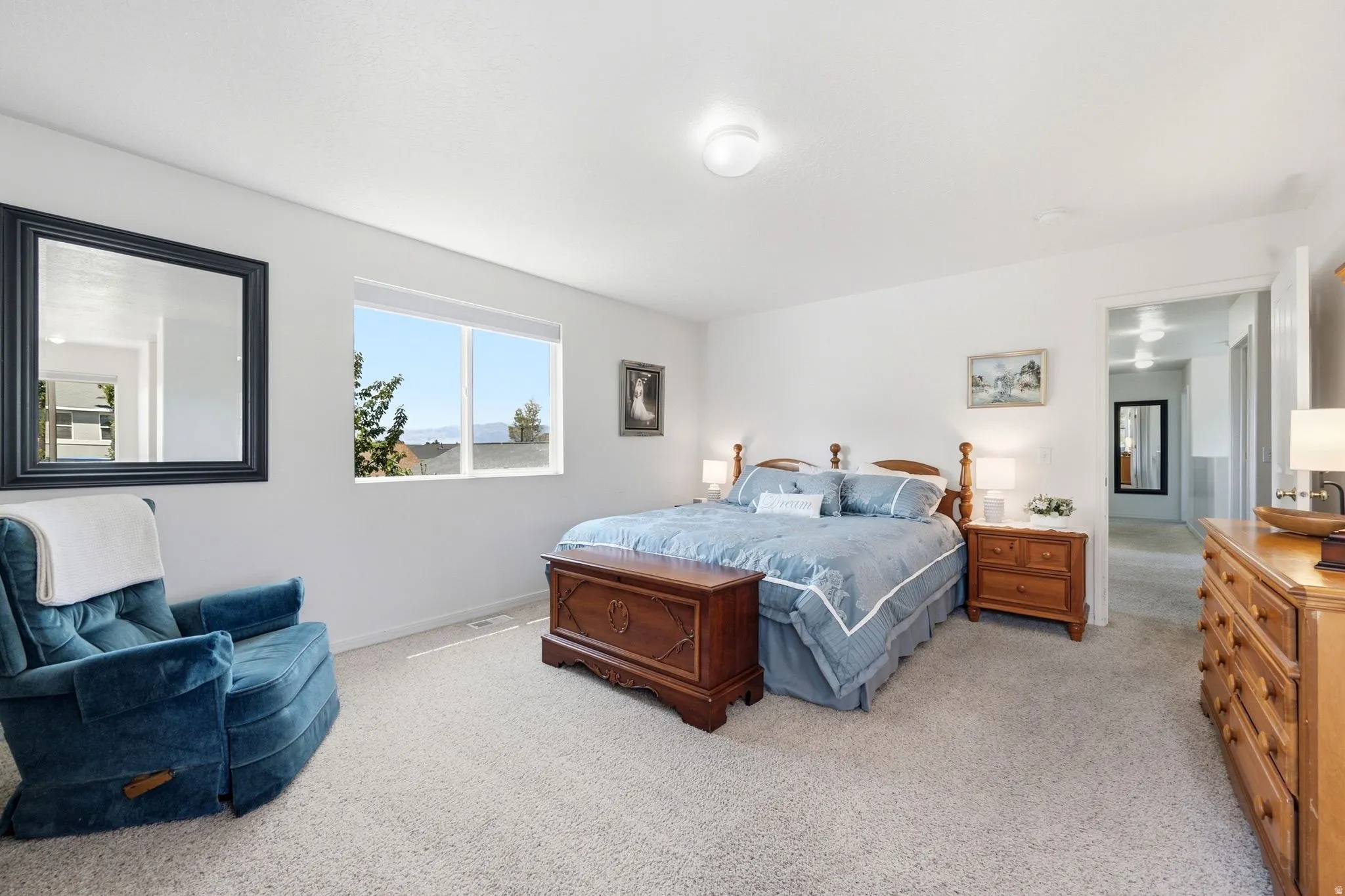 Bright room featuring a large window, neutral wall paint, and light-colored carpet flooring