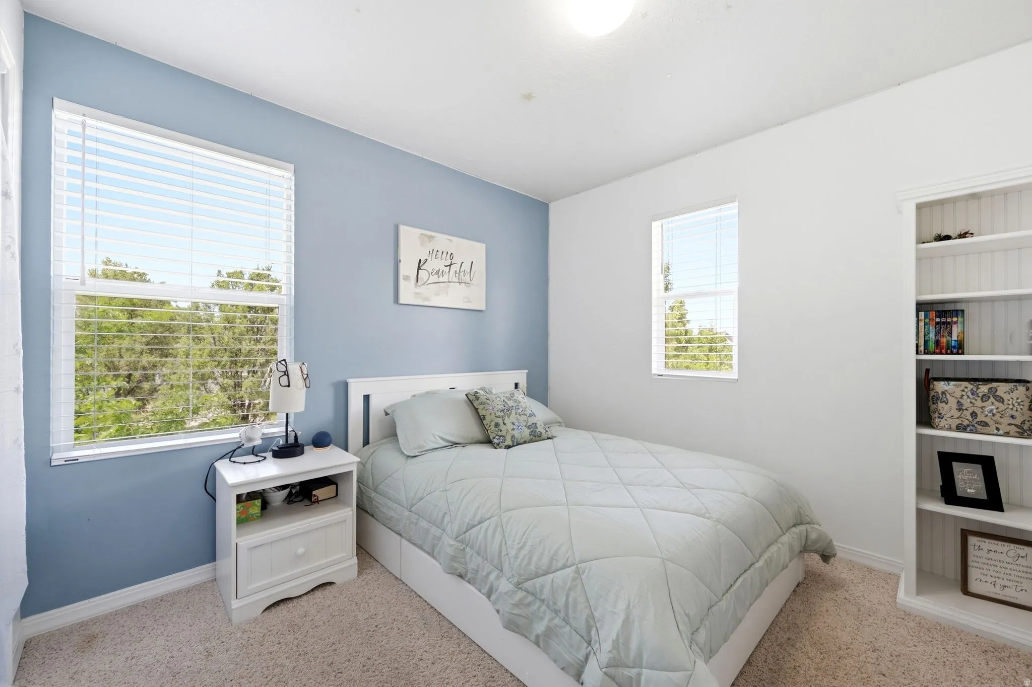 Carpeted interior room featuring a light blue accent wall and two windows with white blinds