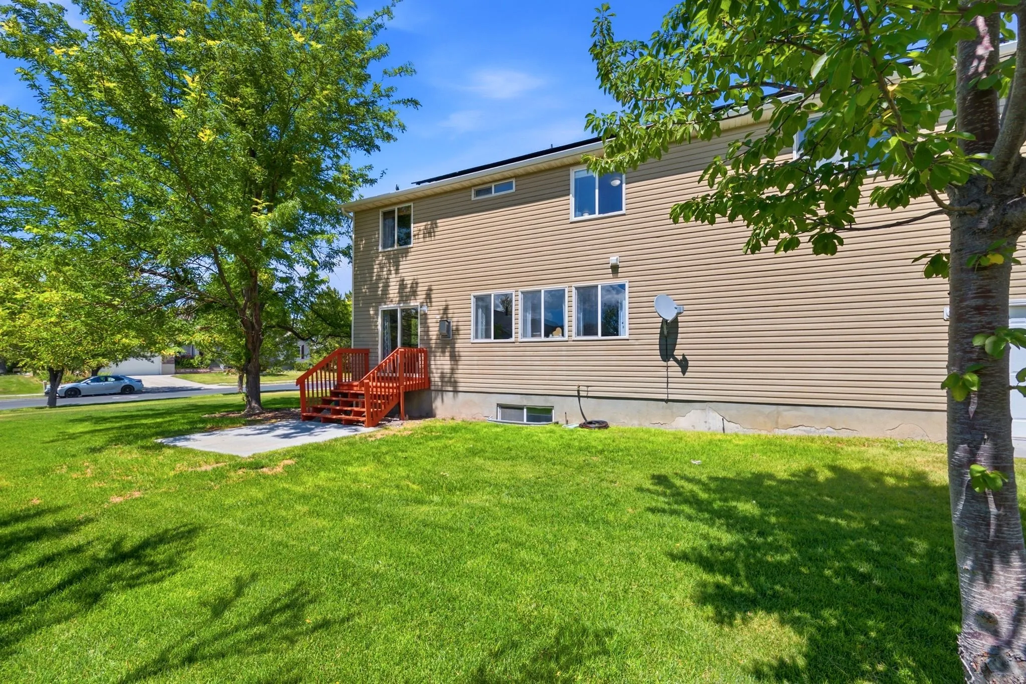 Expansive green lawn with mature trees and a concrete patio