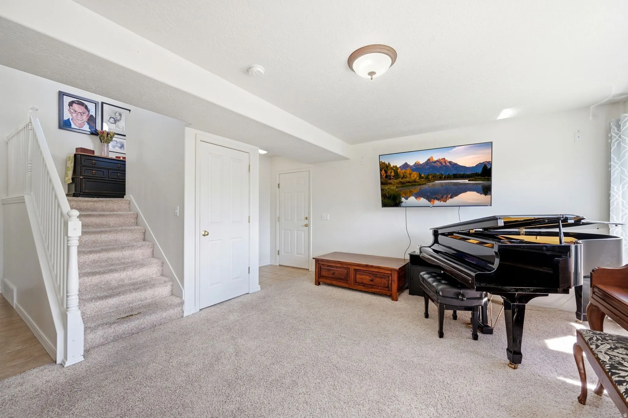 Carpeted staircase with white railings, featuring two white paneled doors and recessed ceiling beams