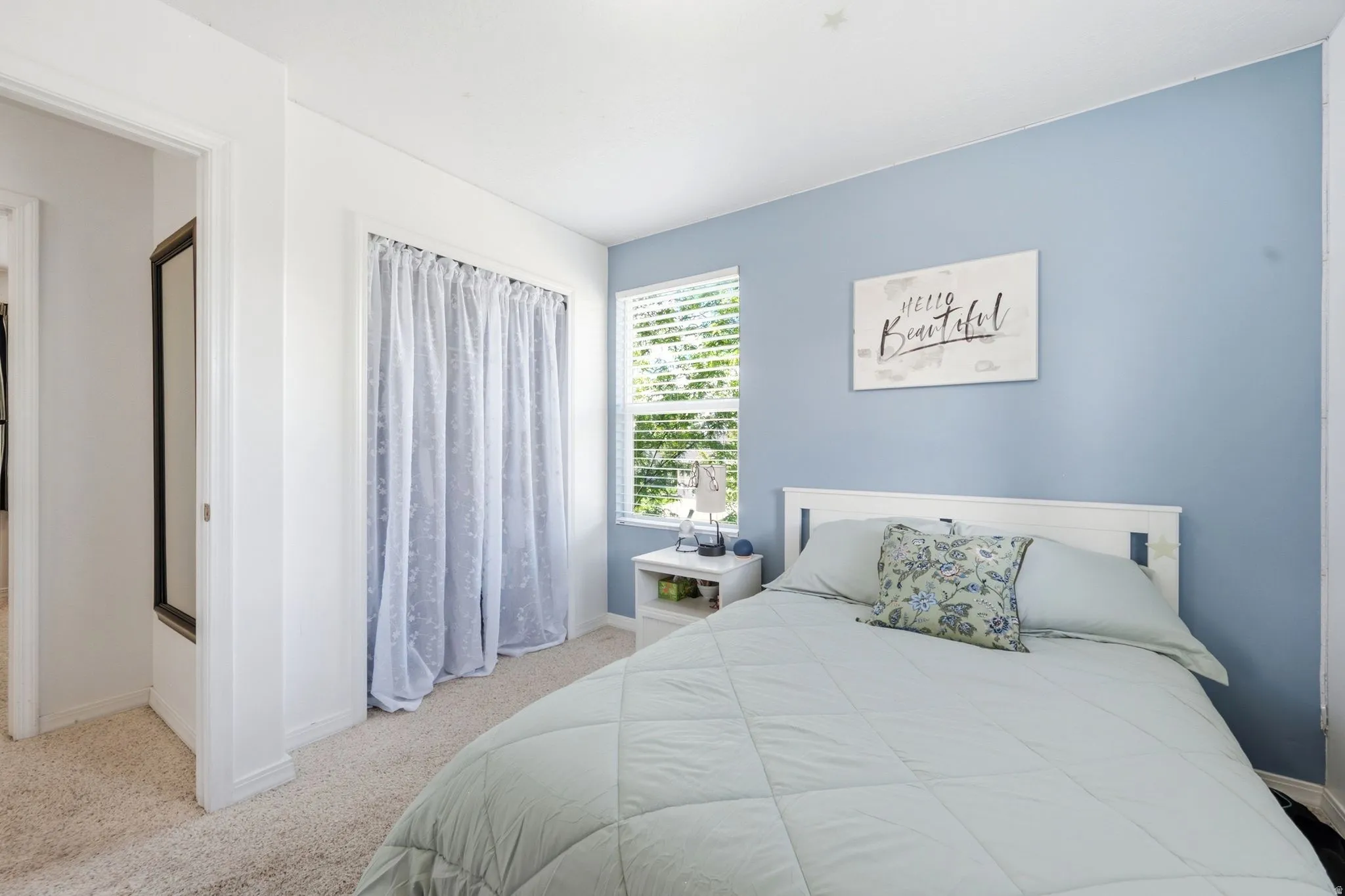 Bedroom featuring carpet flooring, a window with blinds, and a closet with sheer curtains
