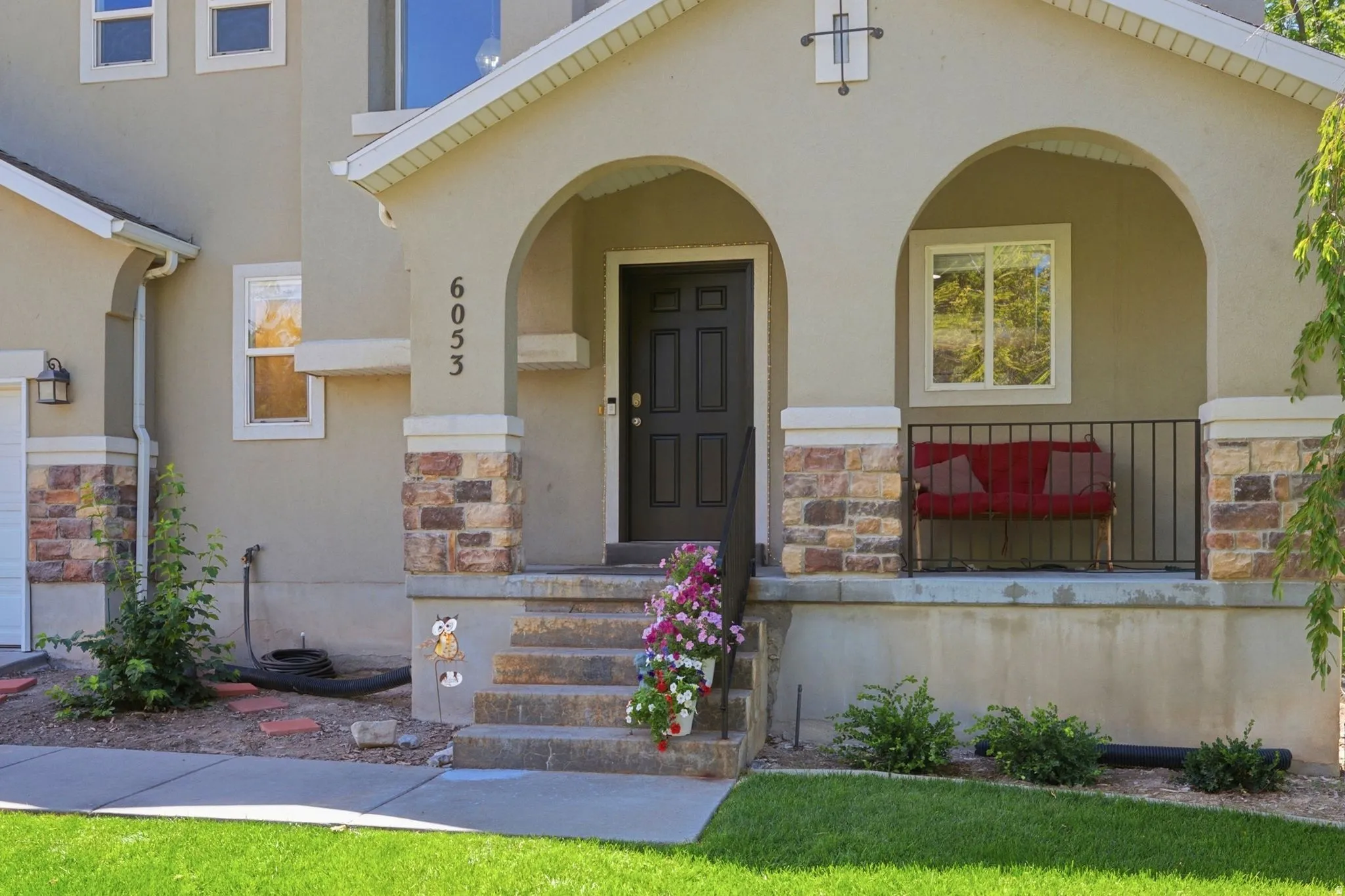 Welcoming arched entryway featuring stone veneer accents, an exterior light fixture, and a dark paneled front door