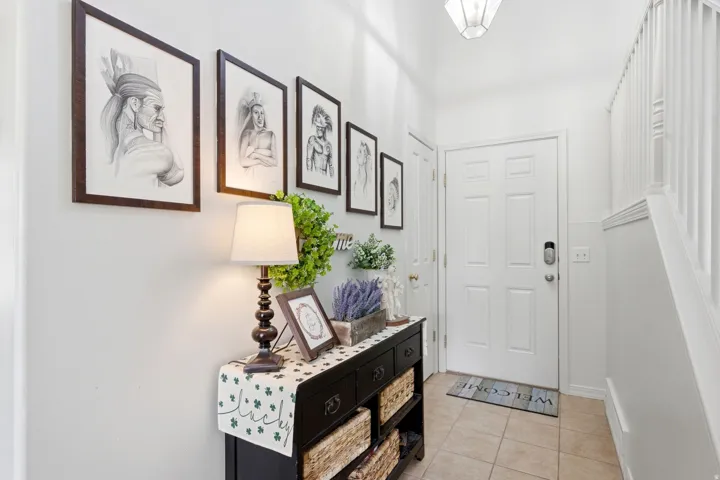 Entryway featuring a white paneled door with smart lock, tile flooring, and white painted walls