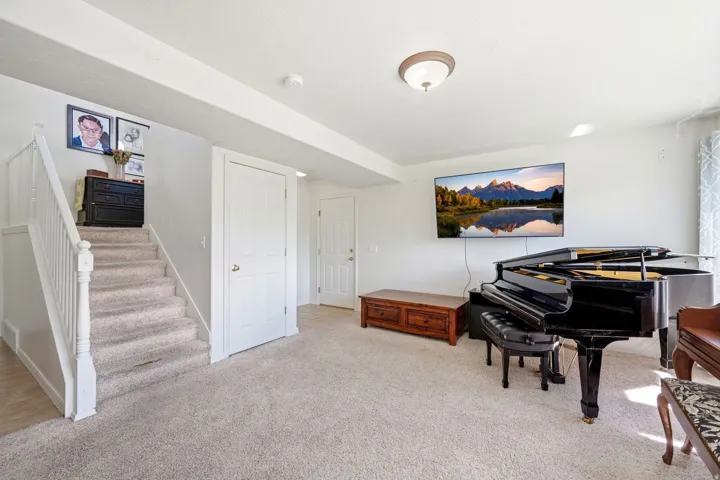 Carpeted staircase with white railings, featuring two white paneled doors and recessed ceiling beams