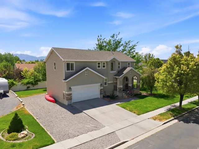 Two-story residence featuring a neutral-toned exterior with a stone accent facade, an attached garage, and a covered front porch