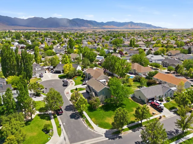 Residential neighborhood featuring mature trees, paved streets with sidewalks, and distant mountains