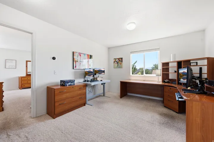 Spacious room featuring carpeting, light-toned walls, and a large window offering outdoor scenery