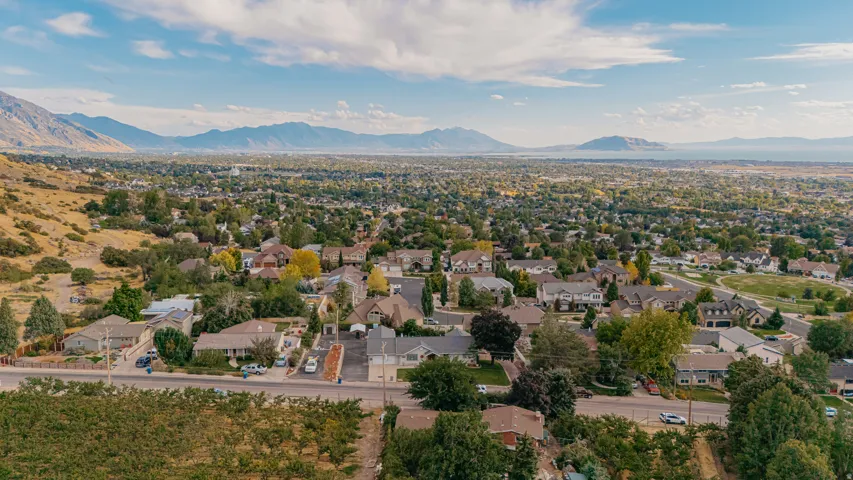 Expansive aerial perspective capturing a residential neighborhood nestled against a mountainous backdrop