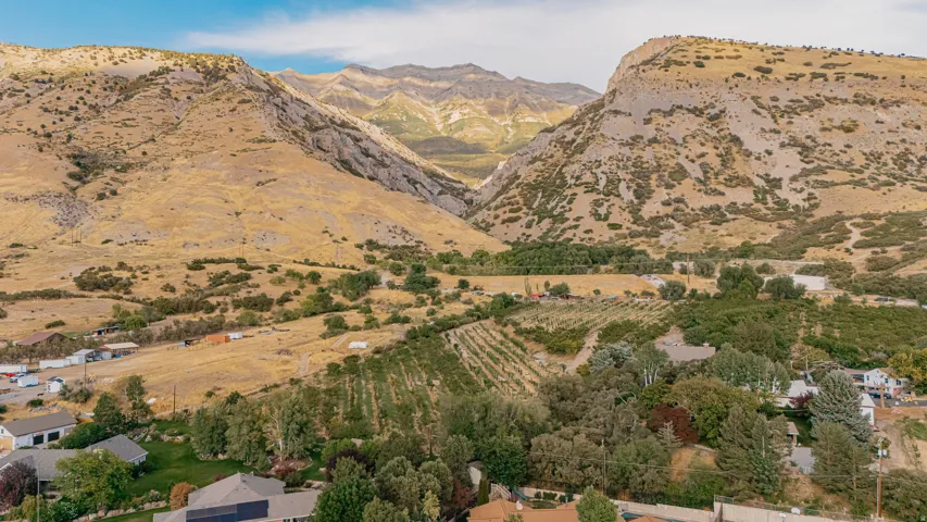 Aerial perspective showcasing a mountain valley, agricultural land, and residential properties