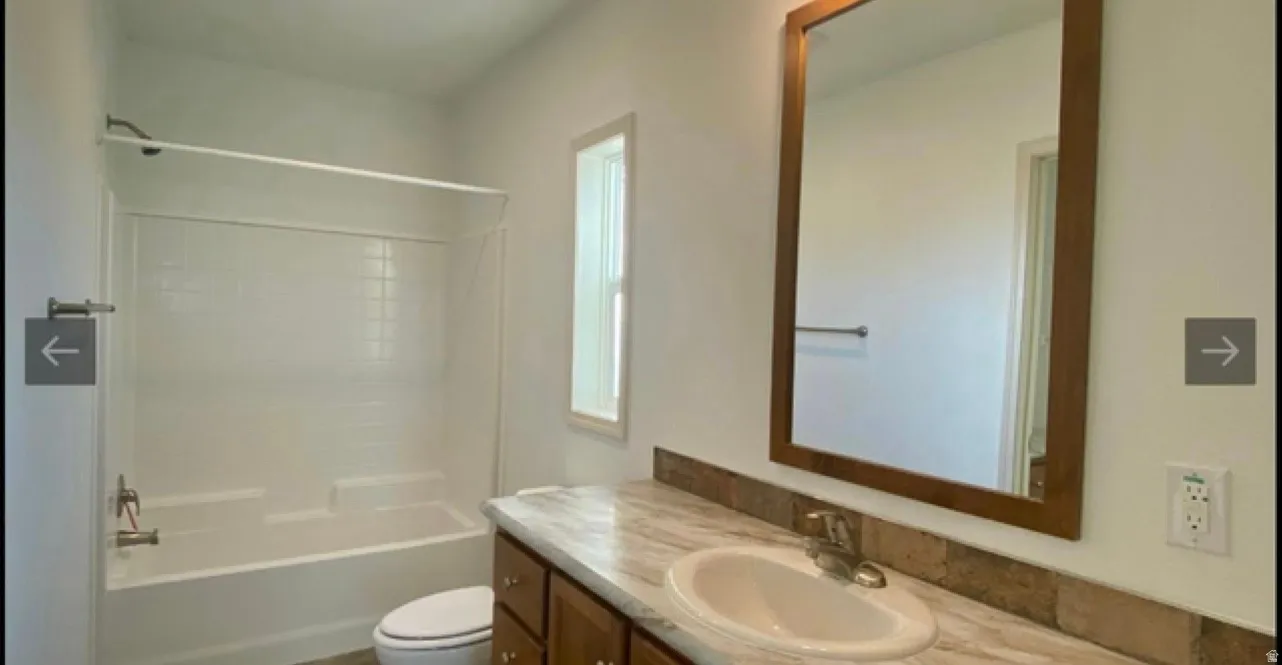 Bathroom featuring a vanity with a white oval sink, wood-finish cabinetry, and a framed mirror