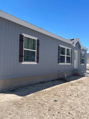 Light gray siding exterior with white window trim and dark wood-tone shutters