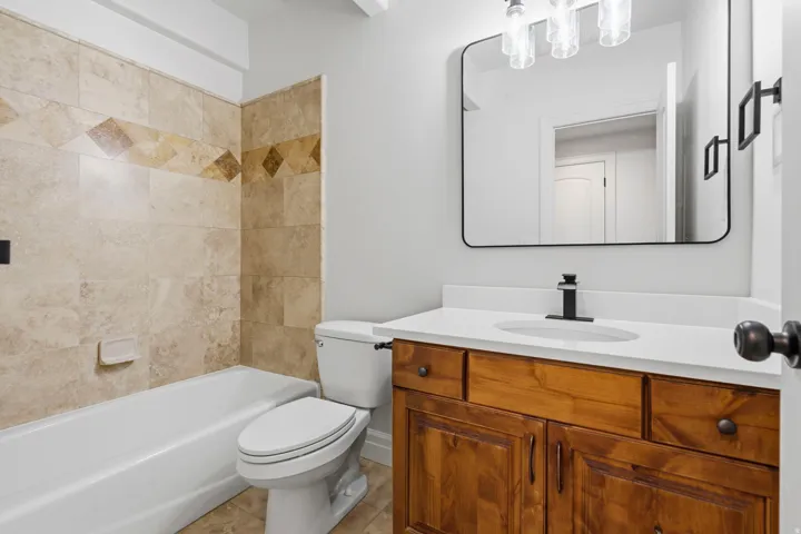Bathroom featuring a wood-finish vanity with a white countertop, an undermount sink, and a black faucet