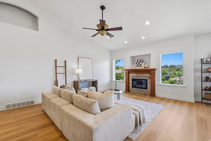 Spacious living area featuring high vaulted ceilings, wood-finish flooring, and a ceiling fan