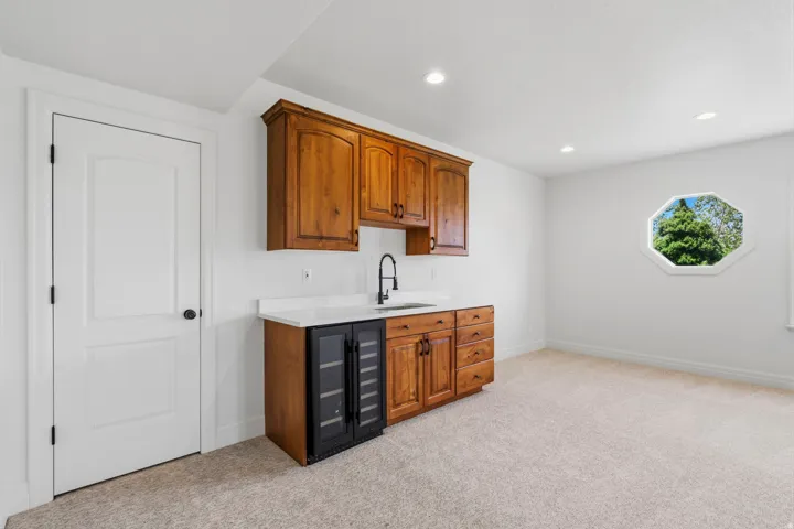 Wet bar featuring wood cabinetry, white countertop, and integrated beverage coolers