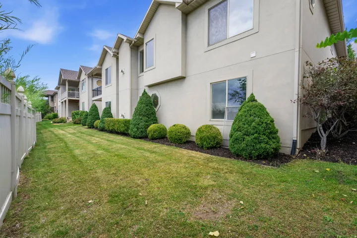 Expansive green space featuring a vinyl privacy fence and landscaped shrubbery