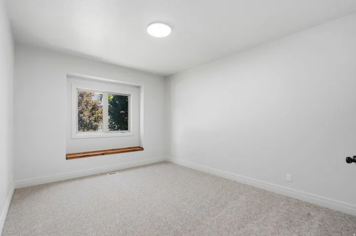 Neutral-toned wall-to-wall carpeting complements the bright white walls and ceiling
