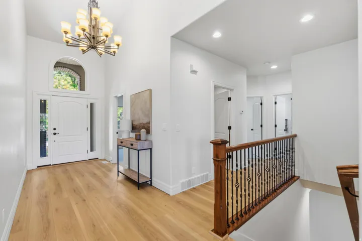 Two-story foyer featuring wood-finish flooring, a decorative chandelier, and an arched transom window above the entry door