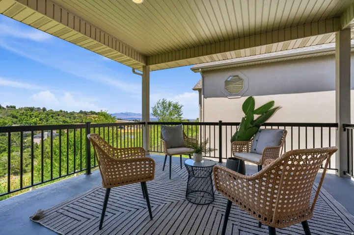 Covered outdoor balcony featuring dark metal railings, a concrete floor, and a beadboard ceiling