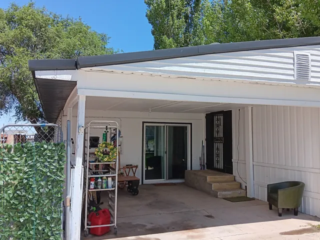 Covered concrete patio entrance featuring white siding, a dark security door, and a sliding glass door
