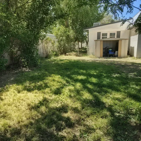 Grassy yard featuring a white storage shed