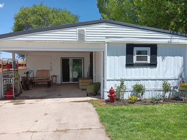White siding exterior with a black metal roof and a covered carport