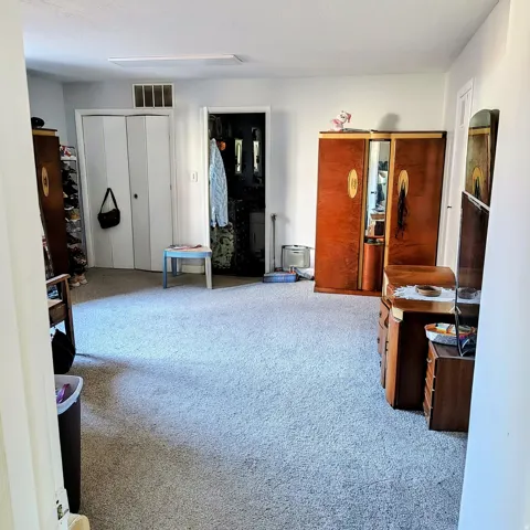 Spacious carpeted room featuring a double bi-fold door closet and a secondary doorway
