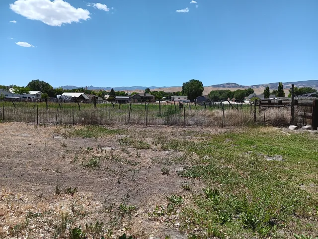 Expansive undeveloped land featuring a partial fence line and distant mountain backdrop
