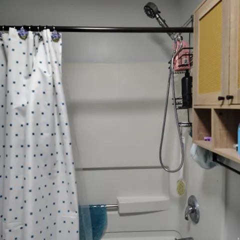 Bathtub and shower combination featuring a multi-function shower head, brushed nickel fixtures, and a shower curtain rod